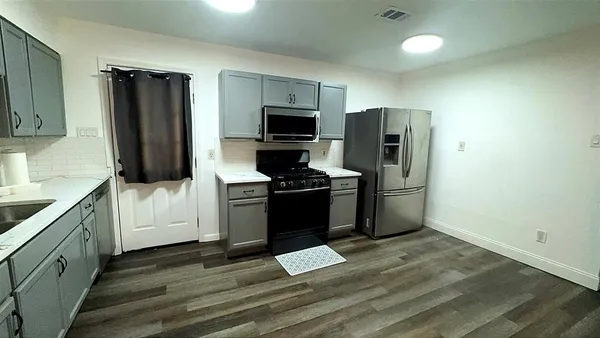 an empty room with wooden floor fan and windows