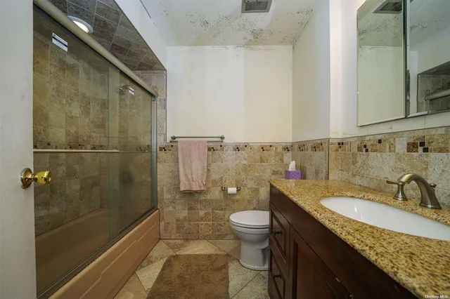 a bathroom with a granite countertop sink a toilet and shower