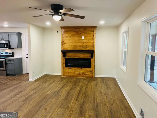 a view of kitchen and empty room with wooden floor