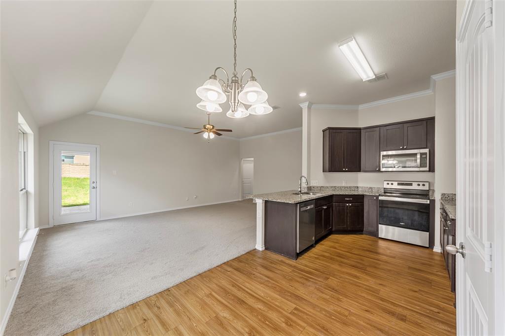 425 Tobin Drive Seagoville, TX 75159 - Photo 20 of 20 Kitchen featuring appliances with stainless steel finishes, dark brown cabinetry, light stone countertops, light wood-type flooring, and open floor plan