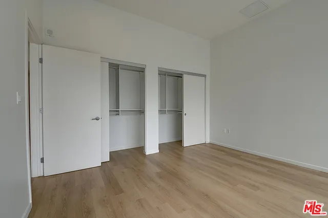 a view of an empty room with wooden floor and closet