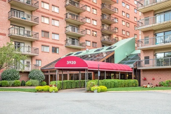 a front view of multi story residential apartment building with yard and green space