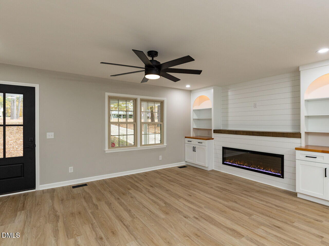 4800 Theys Road Raleigh, NC 27606 - Photo 9 of 43 an empty room with wooden floor a ceiling fan and windows