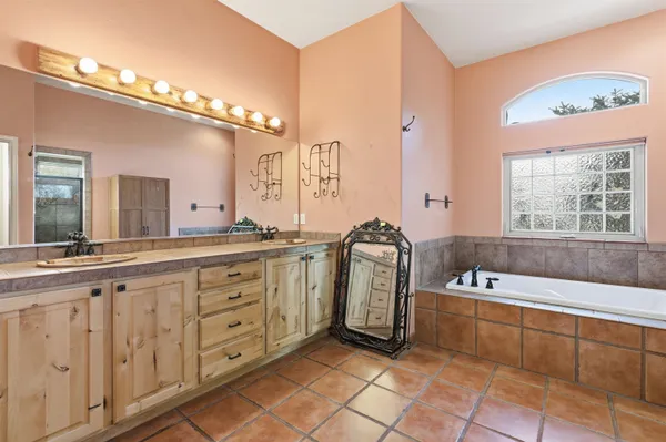 a spacious bathroom with a tub a double vanity sink and a large mirror