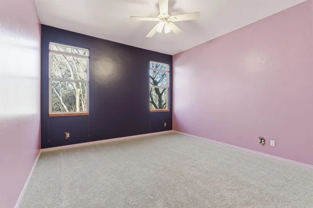 an empty room with windows and fan