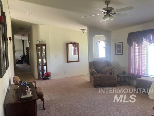 1095 County Road 70 Weiser, ID 83672 - Photo 15 of 44 Carpeted living space featuring an arched architectural detail, overhead ceiling fan with lighting, and a hallway leading to additional areas