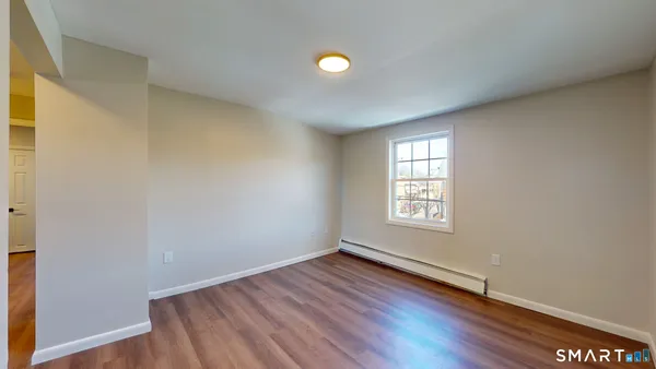 a view of an empty room with window and wooden floor