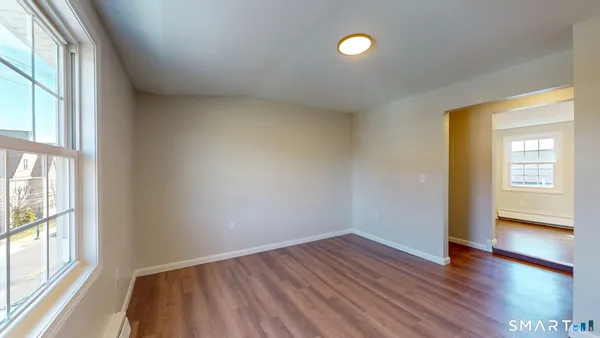 a view of an empty room with wooden floor and a window