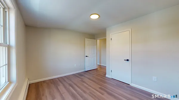 a view of an empty room with closet and a window