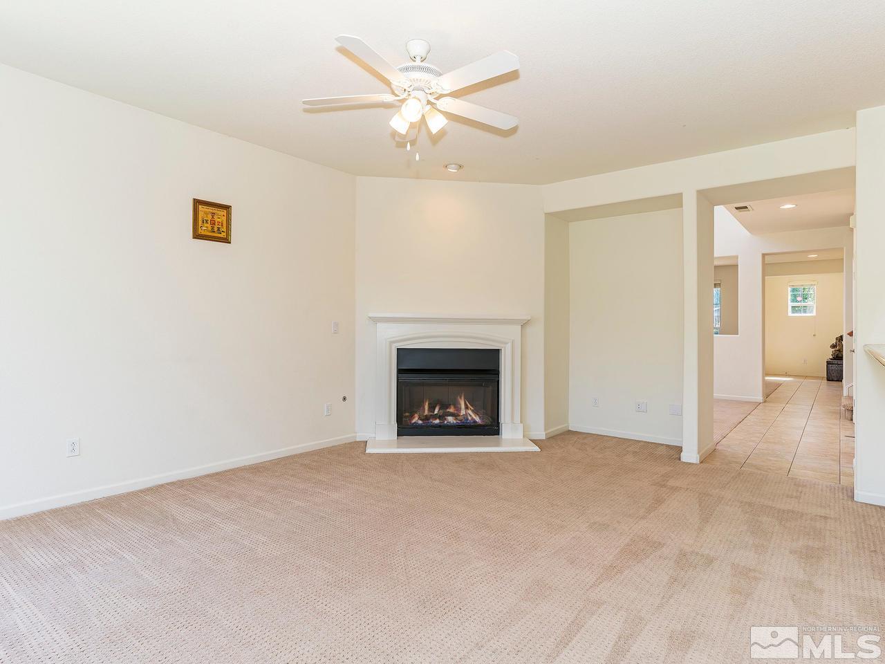 13665 Dressage Court Reno, NV 89521 - Photo 10 of 22 an empty room with a fireplace and a ceiling fan