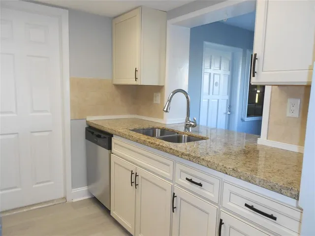 a kitchen with granite countertop white cabinets and a sink