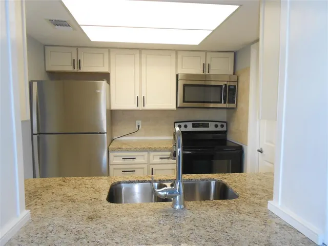 a kitchen with stainless steel appliances granite countertop a refrigerator stove and microwave