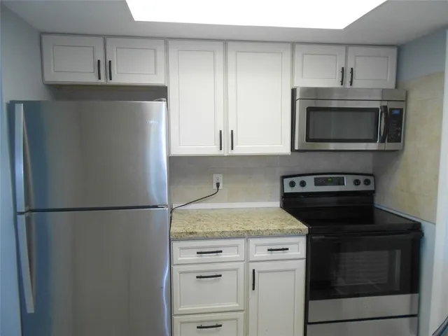 a kitchen with granite countertop white cabinets and stainless steel appliances