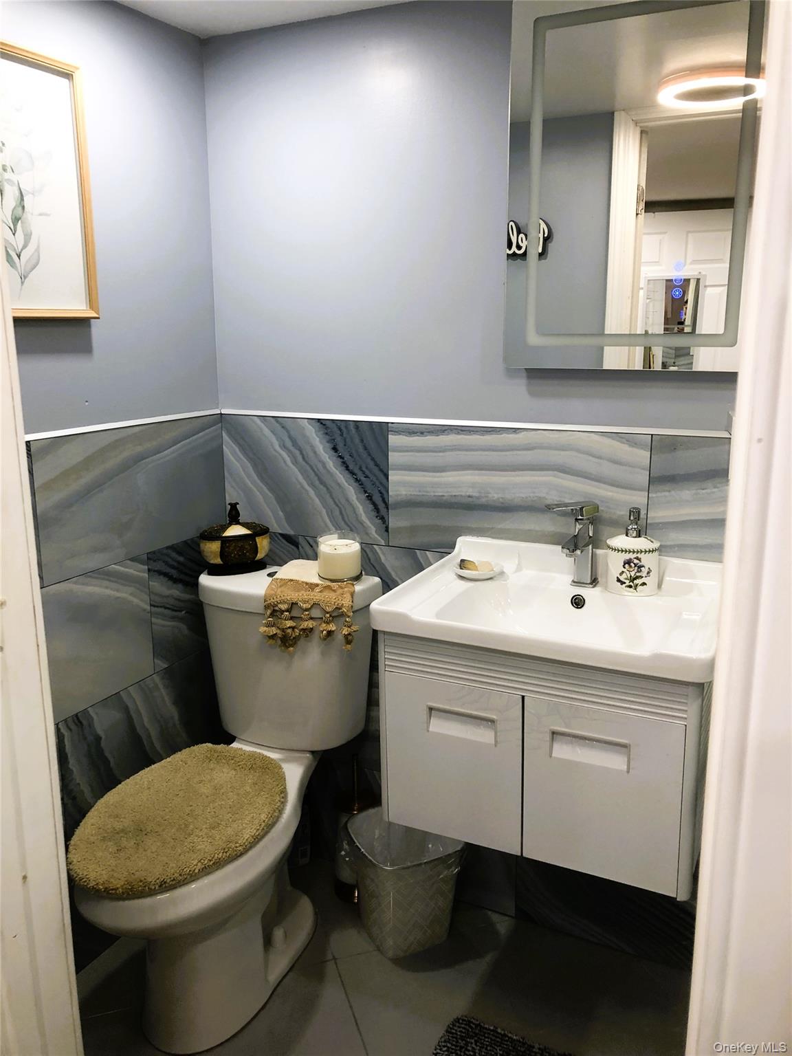 24 Cedar Road Westbury, NY 11590 - Photo 15 of 21 Half bathroom featuring vanity, tile patterned floors, tile walls, and wainscoting