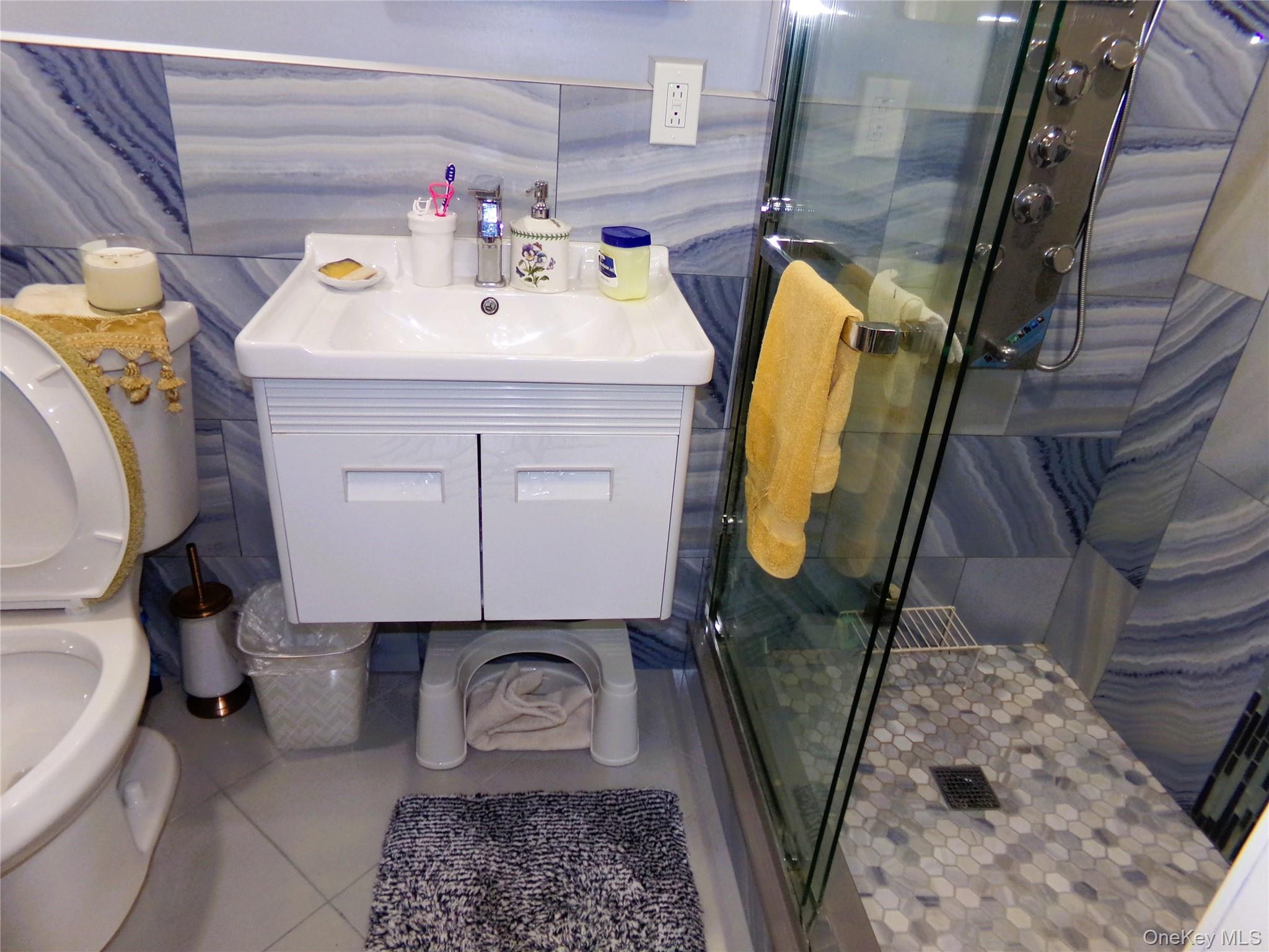 24 Cedar Road Westbury, NY 11590 - Photo 16 of 21 Full bath with tile patterned floors, vanity, and a stall shower