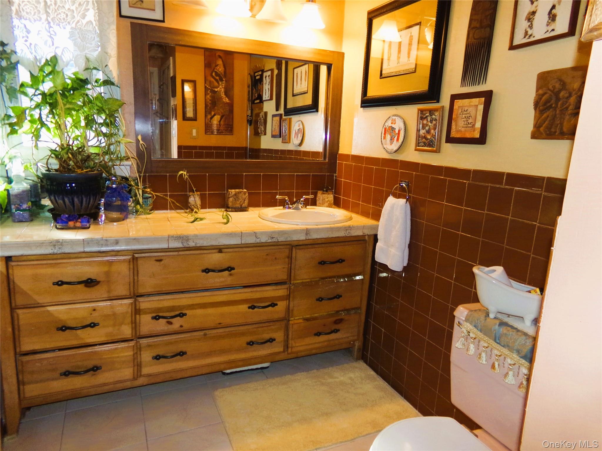 24 Cedar Road Westbury, NY 11590 - Photo 17 of 21 Bathroom with vanity, tile walls, light tile patterned flooring, and wainscoting