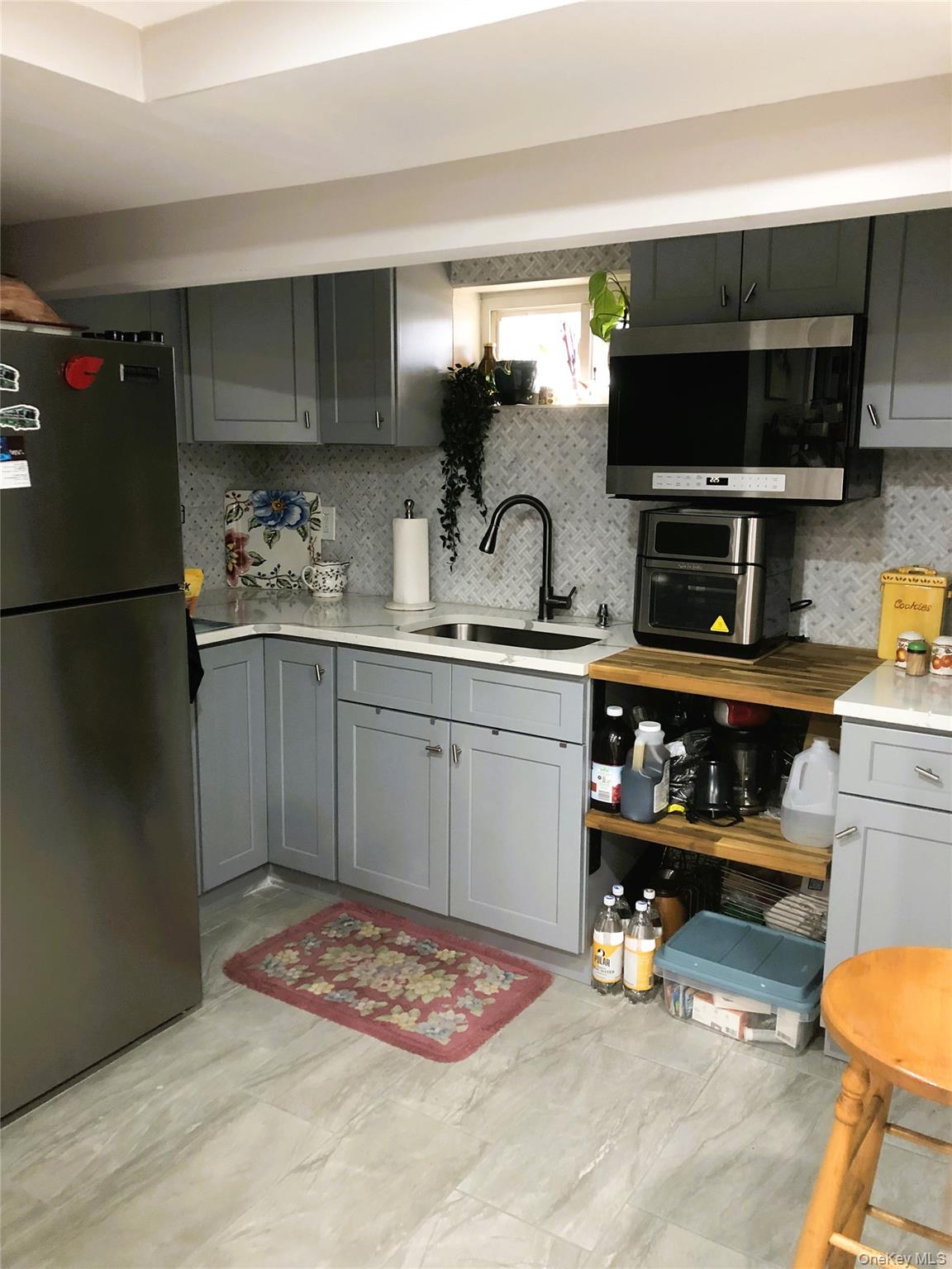 24 Cedar Road Westbury, NY 11590 - Photo 20 of 21 Kitchen featuring gray cabinetry, freestanding refrigerator, stainless steel microwave, and tasteful backsplash