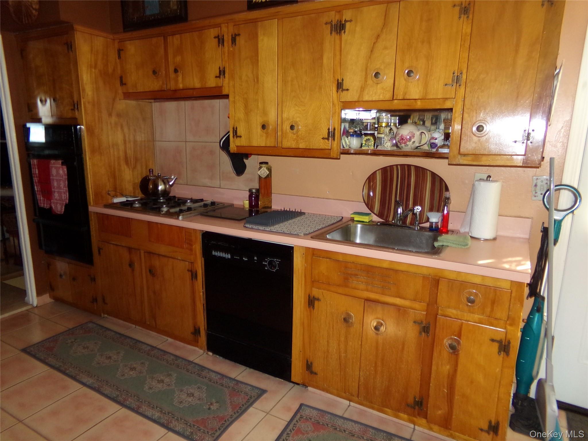 24 Cedar Road Westbury, NY 11590 - Photo 9 of 21 Kitchen with light countertops, black appliances, brown cabinetry, and a warming drawer