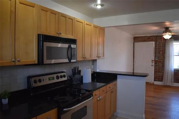 a kitchen with granite countertop wood cabinets and a stove top oven