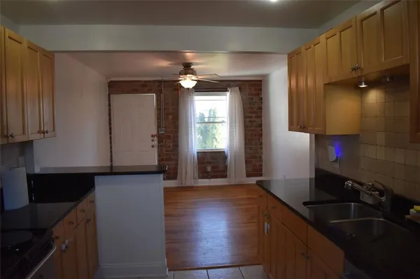 a kitchen with granite countertop a sink cabinets and wooden floor