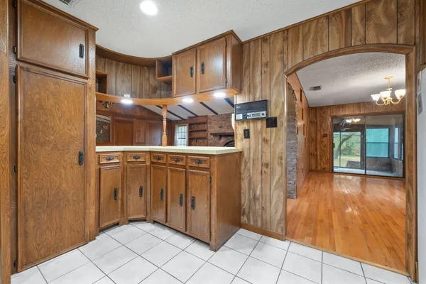 a view of an empty room with glass door and a chandelier fan