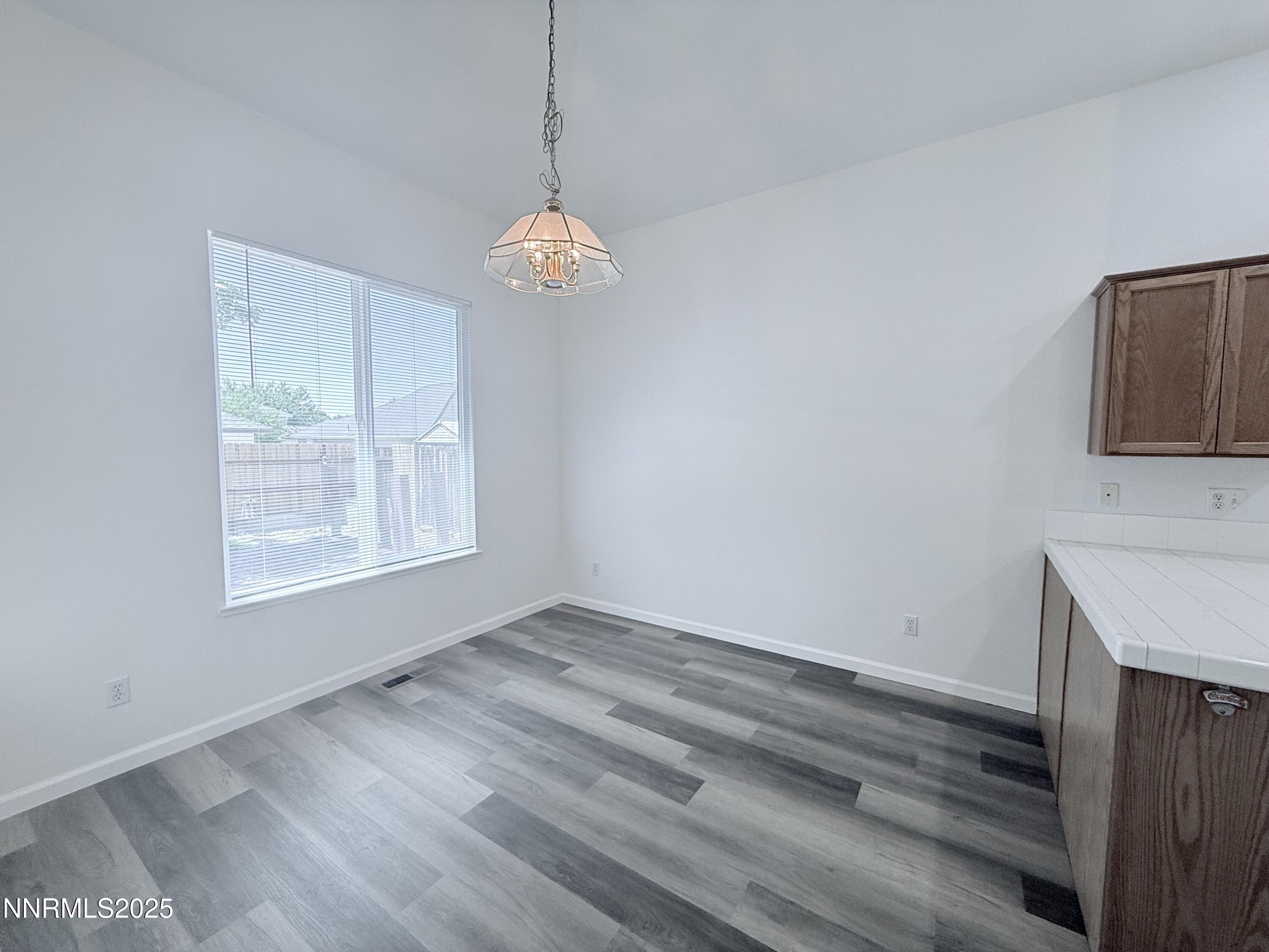 7539 Michaela Drive Reno, NV 89511 - Photo 11 of 33 an empty room with wooden floor and windows