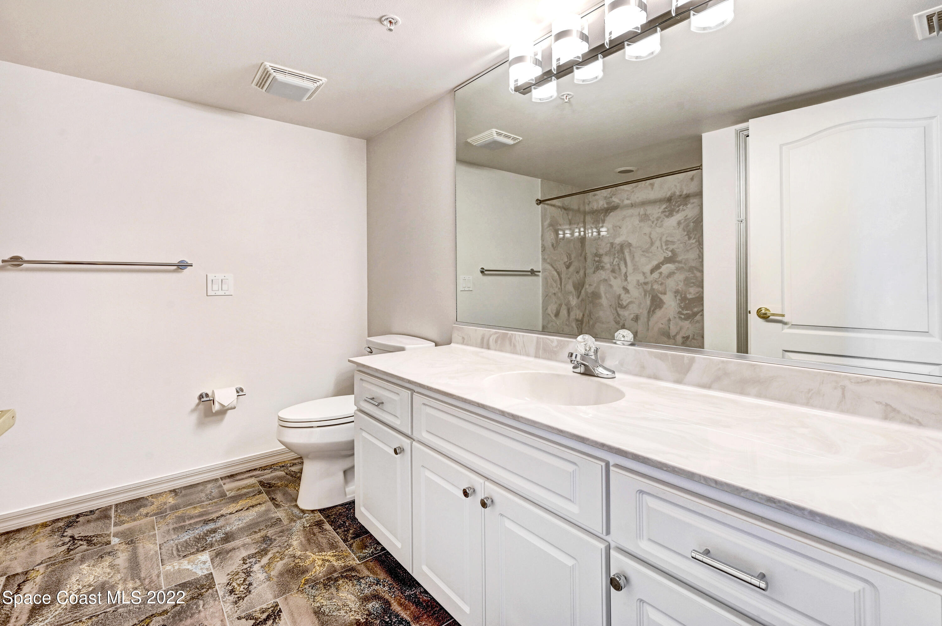 801 Del Rio Way, Unit 602 Merritt Island, FL 32953 - Photo 22 of 36 a bathroom with a granite countertop sink a toilet and a mirror