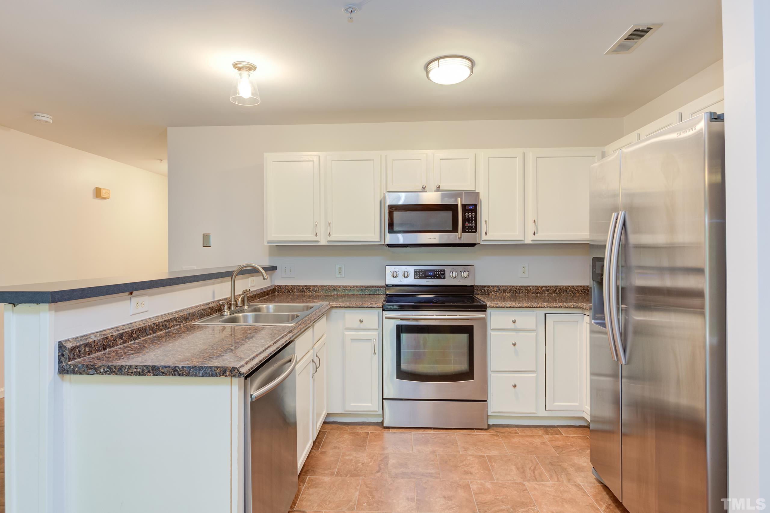 2801 Trailwood Pines Lane, Unit 102 Raleigh, NC 27603 - Photo 11 of 27 a kitchen with stainless steel appliances granite countertop a sink stove and refrigerator
