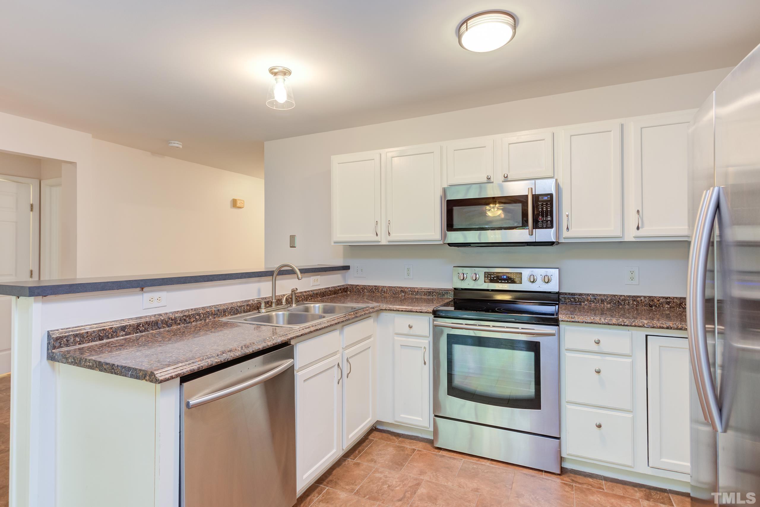 2801 Trailwood Pines Lane, Unit 102 Raleigh, NC 27603 - Photo 12 of 27 a kitchen with stainless steel appliances granite countertop a sink stove and microwave