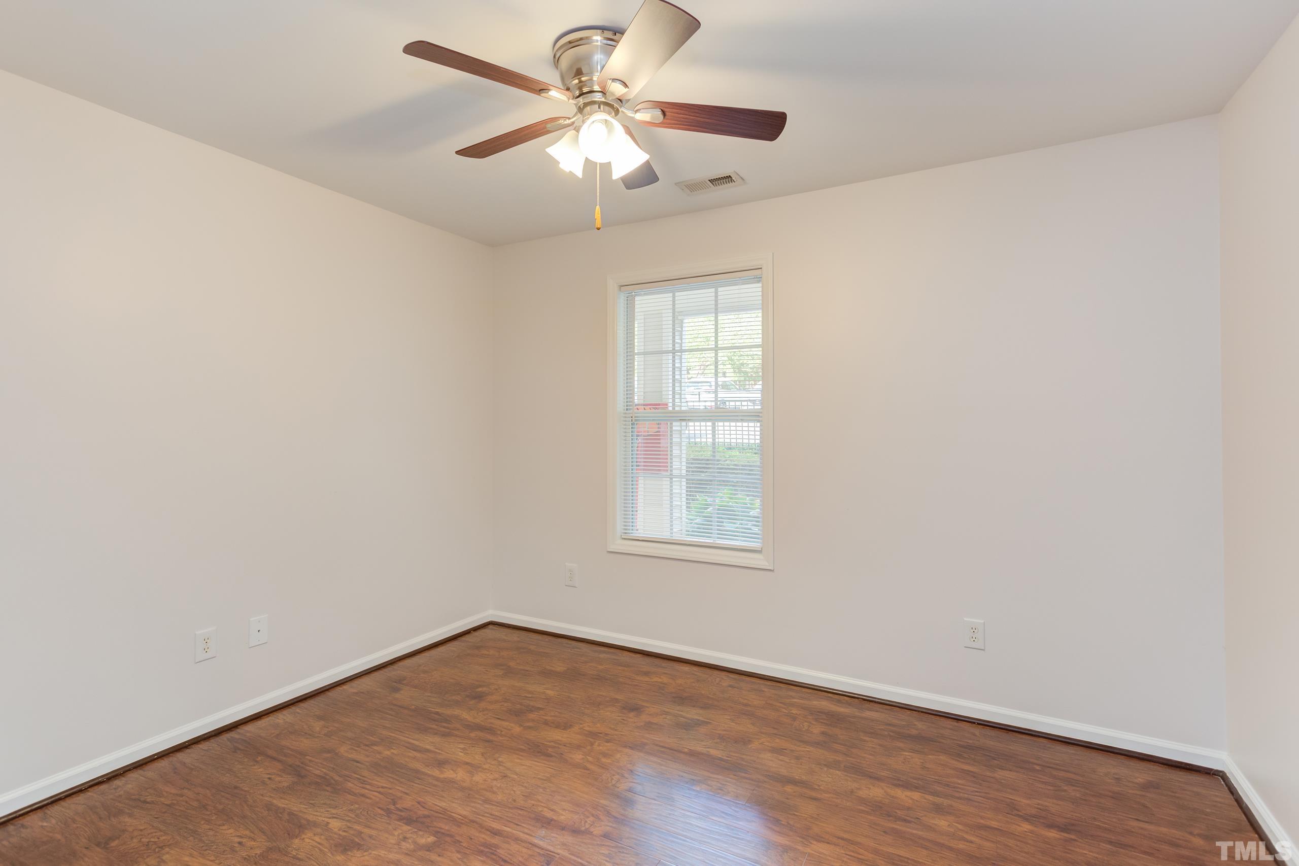 2801 Trailwood Pines Lane, Unit 102 Raleigh, NC 27603 - Photo 15 of 27 an empty room with wooden floor fan and windows