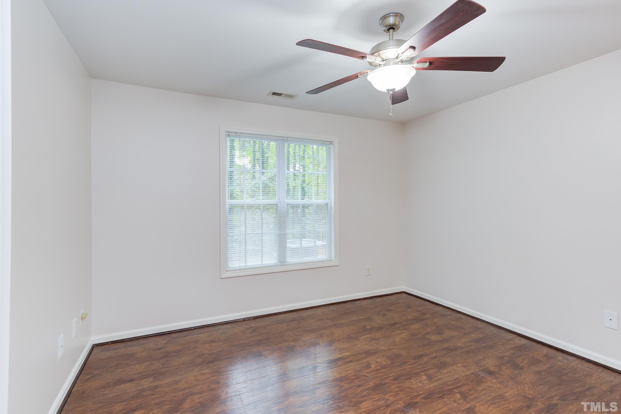 2801 Trailwood Pines Lane, Unit 102 Raleigh, NC 27603 - Photo 17 of 27 an empty room with wooden floor chandelier fan and windows