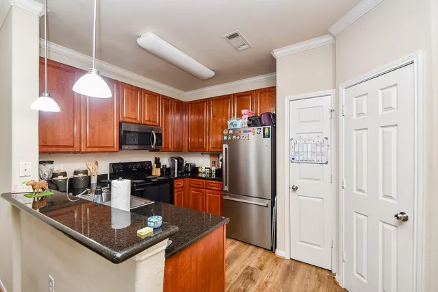 a kitchen with stainless steel appliances granite countertop a refrigerator a sink dishwasher a stove with wooden cabinets and floor