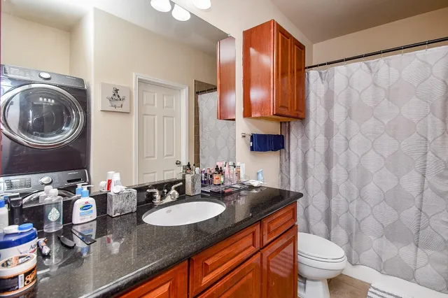 a bathroom with a granite countertop sink a toilet and a mirror