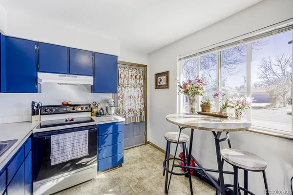 a kitchen with stainless steel appliances granite countertop a stove a refrigerator a dining table and chairs with wooden floor