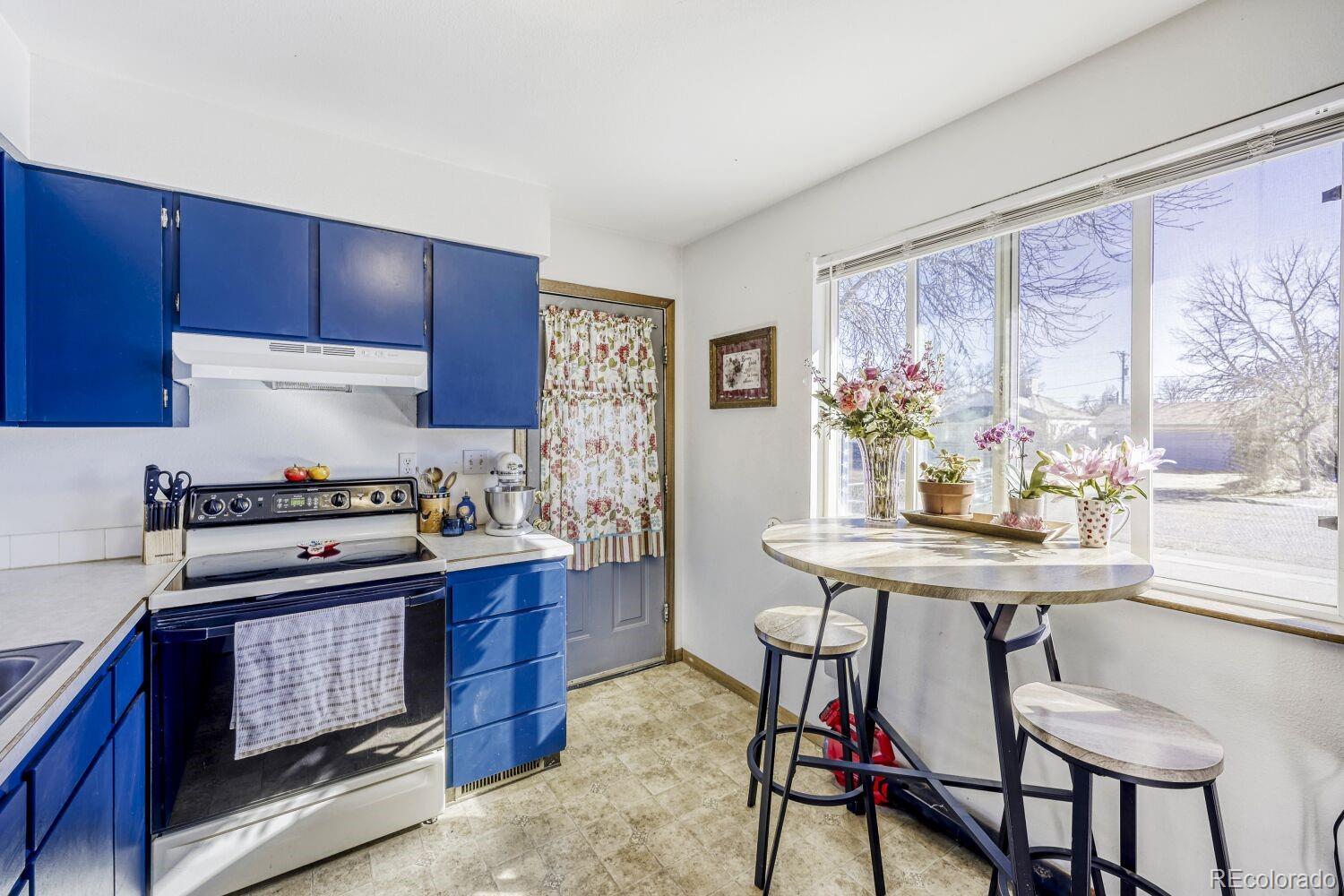 111 7th Street Fort Lupton, CO 80621 - Photo 11 of 22 a kitchen with stainless steel appliances granite countertop a stove a refrigerator a dining table and chairs with wooden floor