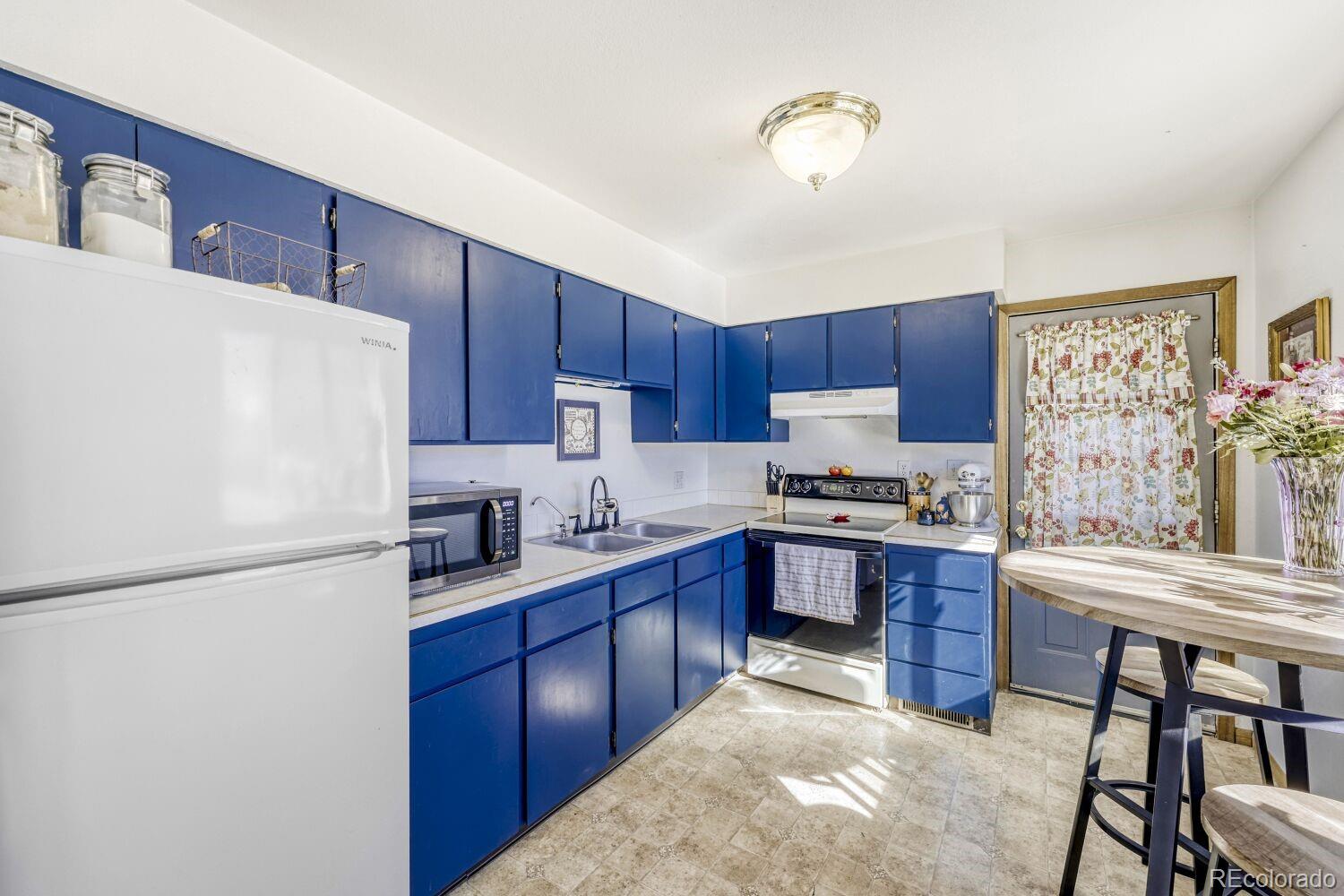111 7th Street Fort Lupton, CO 80621 - Photo 9 of 22 a kitchen with granite countertop a stove a sink dishwasher a refrigerator and a dining table with wooden floor