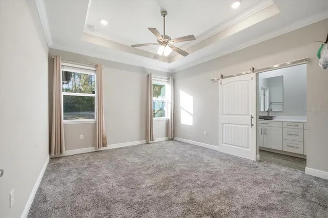en empty room with chandelier fan and kitchen view