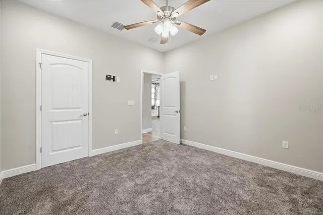 a view of an empty room and chandelier fan