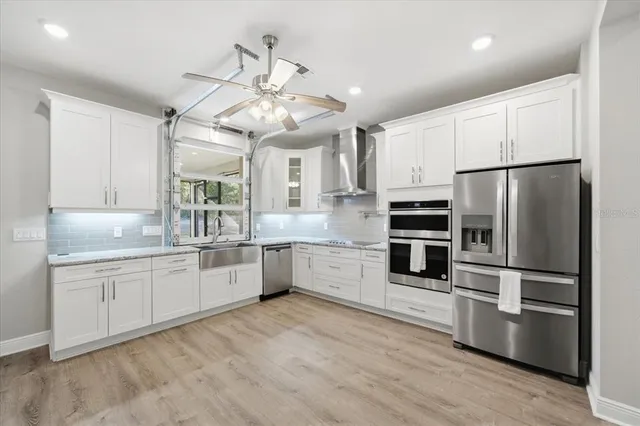a large kitchen with cabinets wooden floor and stainless steel appliances
