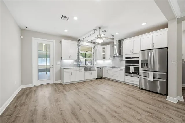 a large kitchen with stainless steel appliances a refrigerator and a sink