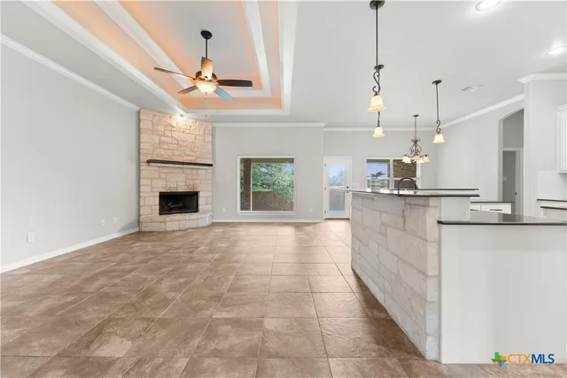 a view of an empty room and kitchen with fireplace