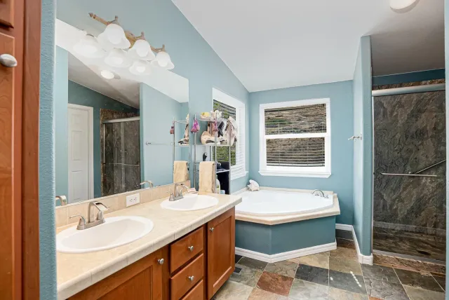 a bathroom with a double vanity sink mirror and bathtub