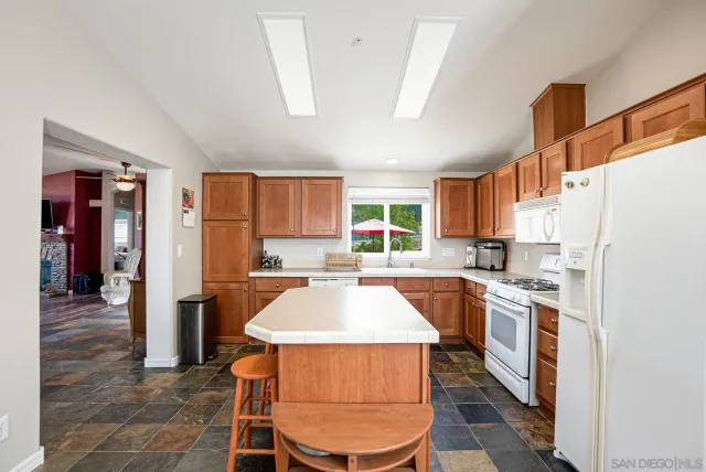 a kitchen with stainless steel appliances a stove a sink dishwasher a refrigerator white cabinets and wooden floor