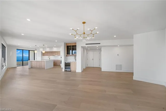 a view of an empty room with kitchen and window
