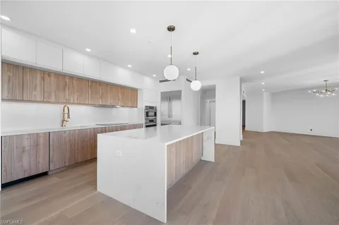 a large kitchen with kitchen island a sink a center island stainless steel appliances and a chandelier