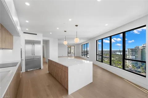 a large kitchen with stainless steel appliances a large counter top a refrigerator and a sink