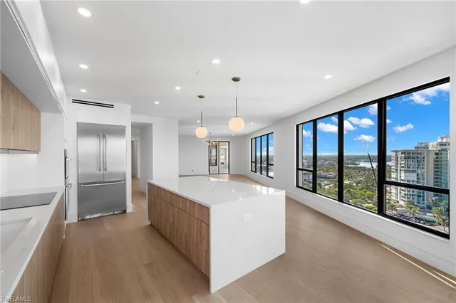 a large kitchen with stainless steel appliances a large counter top a refrigerator and a sink