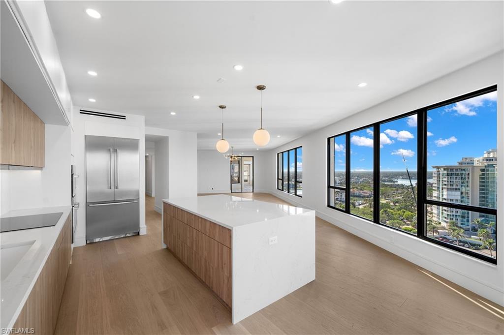 4451 Gulf Shore Boulevard North, Unit 2002 Naples, FL 34103 - Photo 9 of 36 a large kitchen with stainless steel appliances a large counter top a refrigerator and a sink