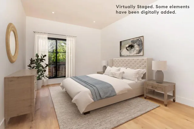 a bedroom with a bed painting on wall and a large window