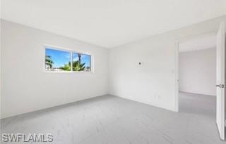 1018 Manatee Road, Unit E107 Naples, FL 34114 - Photo 6 of 15 Bright room with large window, featuring white walls, light-toned flooring, and a white interior door